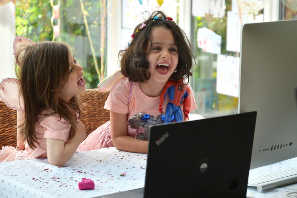 BUCKINGHAMSHIRE, UNITED KINGDOM - MAY 14: Twin sisters, daughters of the photographer, enjoy a Zoom party for their fourth birthday, on May 14, 2020 in Buckinghamshire, United Kingdom. The prime minister announced the general contours of a phased exit from the current lockdown, adopted nearly two months ago in an effort curb the spread of Covid-19. (Photo by Jim Dyson/Getty Images)