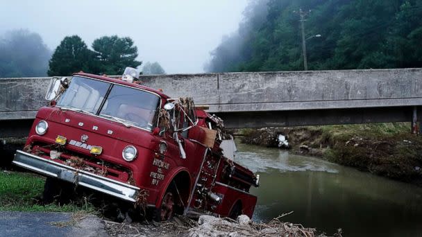 PHOTO: A fire truck is seen hangin over the edge of the water propped against a bridge, Aug. 3, 2022, in Hindman, Ky., after massive flooding carried the fire truck towards the water.   (Brynn Anderson/AP)