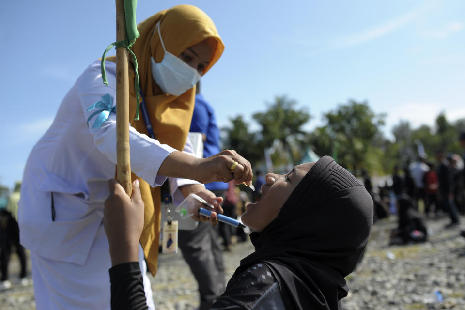 A medical worker gives drops of vaccine to a girl during a polio immunization campaign at Sigli Town Square in Pidie, Aceh province, Indonesia, Monday, Nov. 28, 2022. Indonesia has begun a campaign against the poliovirus in the the country's conservative province after several children were found infected with the highly-contagious disease that was declared eradicated in the country less than a decade ago. (AP Photo/Riska Munawarah)