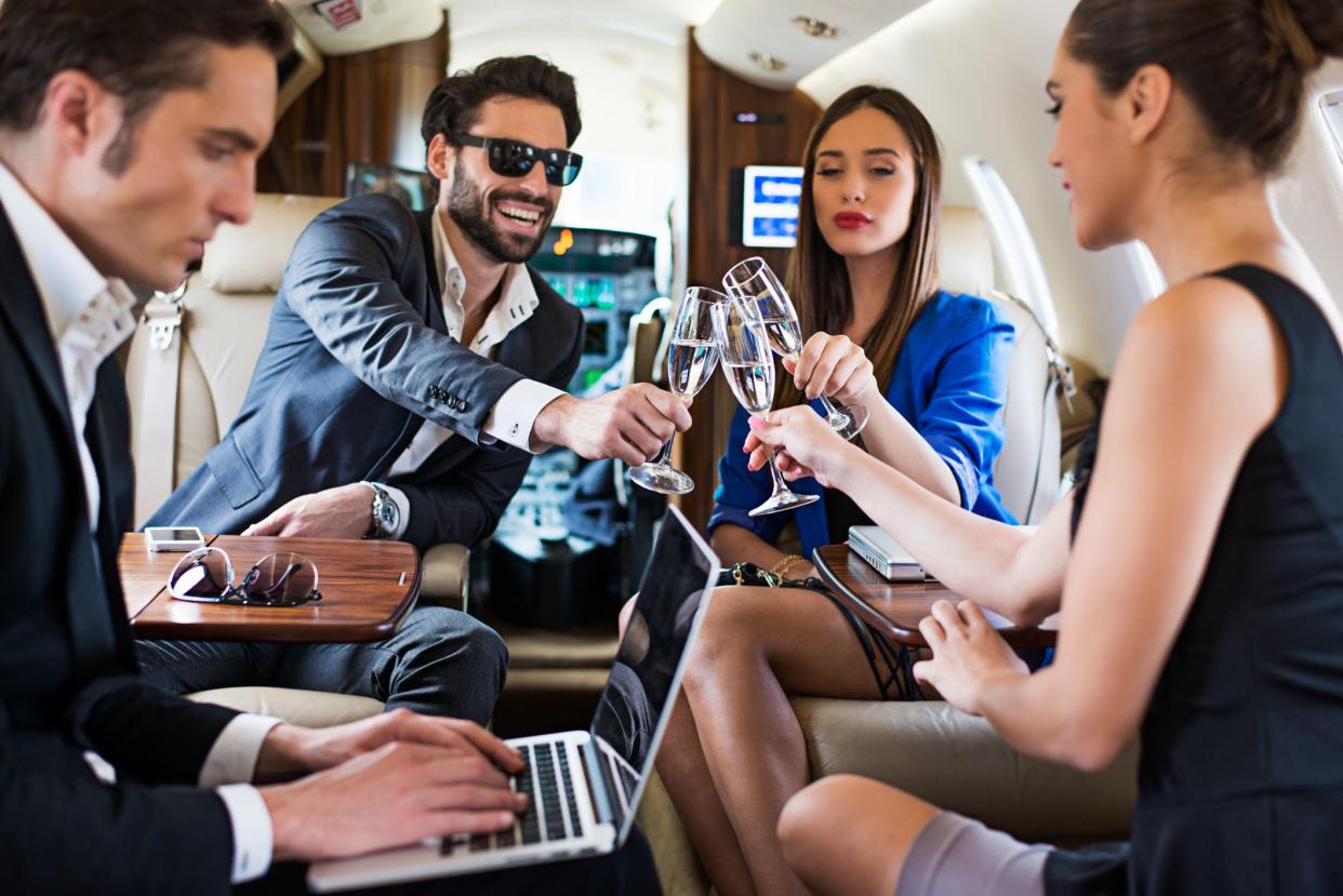 Group of young people traveling with private jet airplane and enjoying the teamwork with champagne.