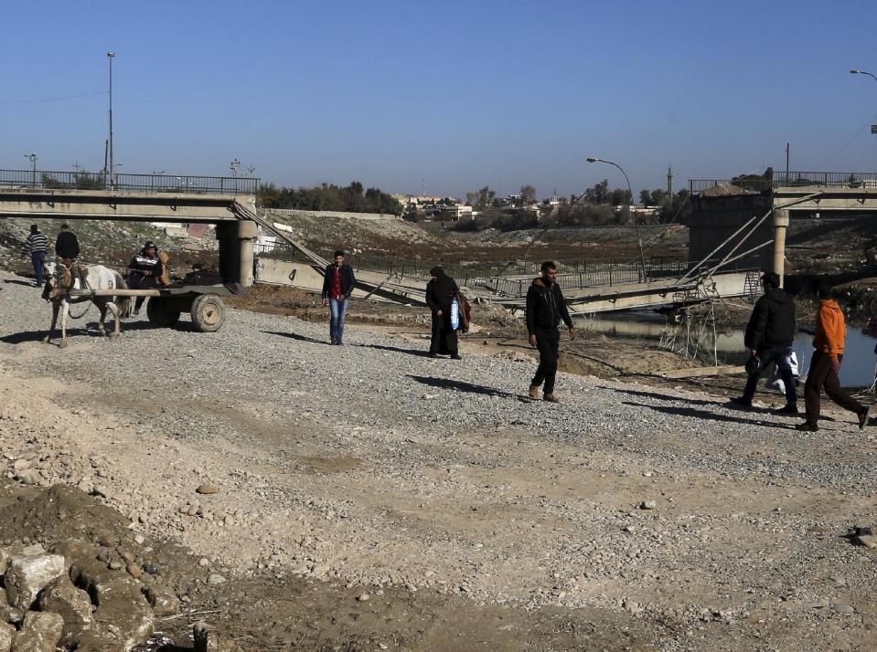 Civilians cross on a makeshift river next to a bridge destroyed by Islamic State militants in a neighborhood recently liberated from Islamic State on the eastern side of Mosul, Iraq, Thursday, Jan. 12, 2017. Small stalls and carts have sprung up outside the bombed-out restaurants and cafes in eastern Mosul, selling fresh vegetables, cigarettes and cellphones to the thousands of civilians still living in neighborhoods where the Iraqi military has driven out the extremists of the Islamic State group. (AP Photo/ Khalid Mohammed)