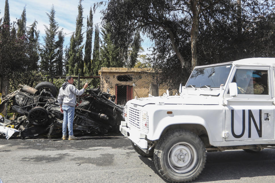 A U.N peacekeeper vehicle passes next to a destroyed car in the southern outskirts of Tyre, Lebanon, Wednesday, March 13, 2024. An Israeli drone strike Wednesday targeting a car in southern Lebanon near the coastal city of Tyre killed a member of Hamas and at least one other person. (AP Photo/Mohammad Zaatari)