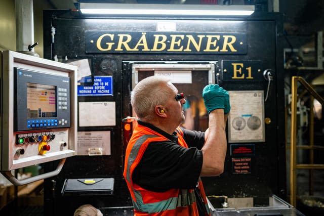 A worker checks the quality of a freshly minted £1 coin