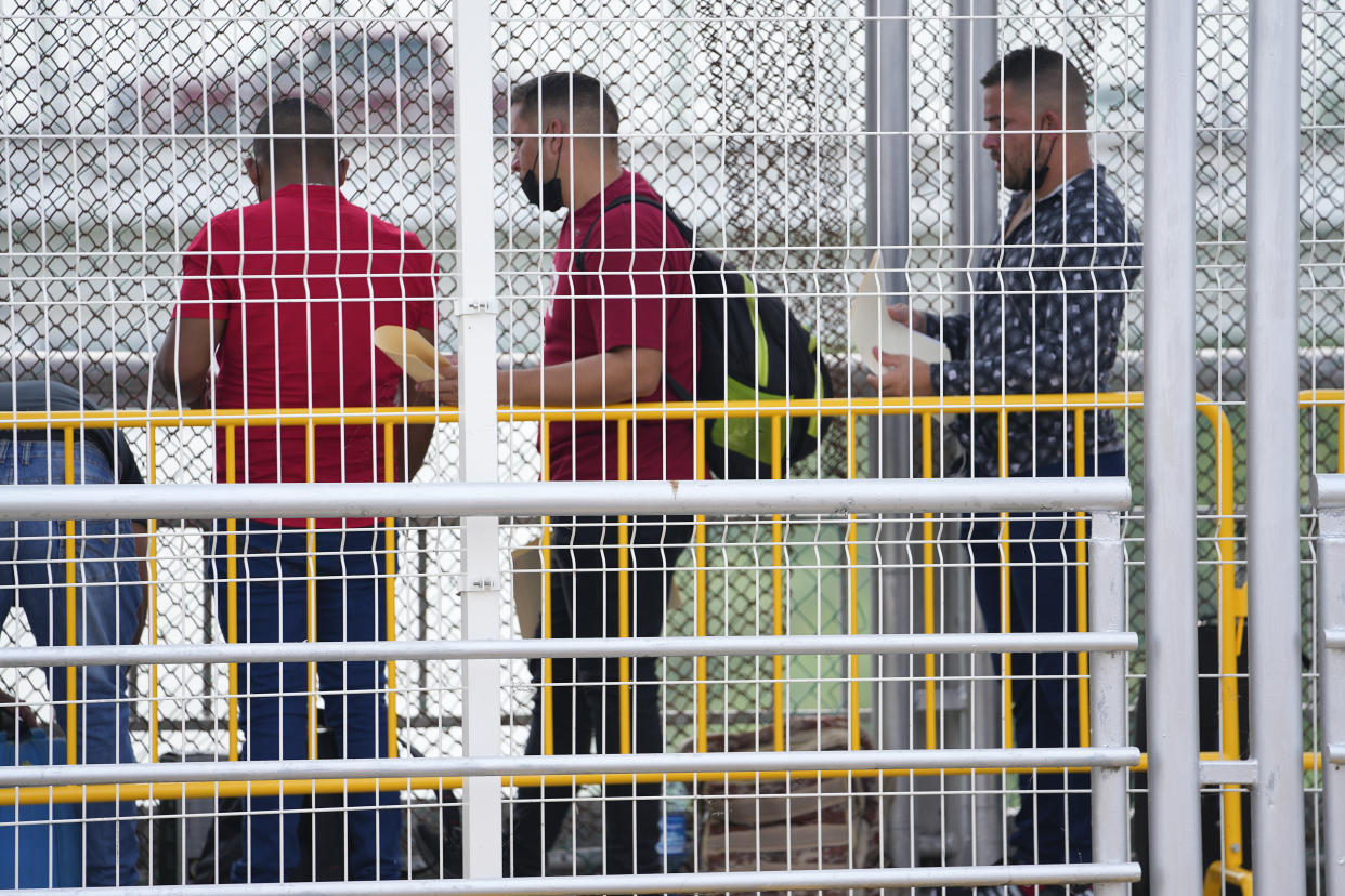 Migrants hold documents as they wait for their appointments to be processed by U.S. immigration officials on the McAllen-Hidalgo International Bridge, Friday, May 12, 2023, in Hidalgo, Texas. (AP Photo/Julio Cortez)