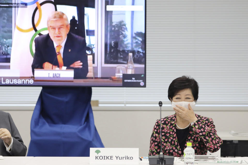 Tokyo Gov. Yuriko Koike, right, reacts before an on-line meeting focused on how to pull off the delayed Tokyo Games, in Tokyo, Thursday, Sept. 24, 2020. IOC President Thomas Bach delivered a pep talk to Japanese government officials and local organizers on Thursday that included suggestions that “hundreds of millions”of doses COVID-19 vaccines would be available before the postponed Olympic are to open on July 23, 2021. (Du Xiaoyi/Pool Photo via AP)