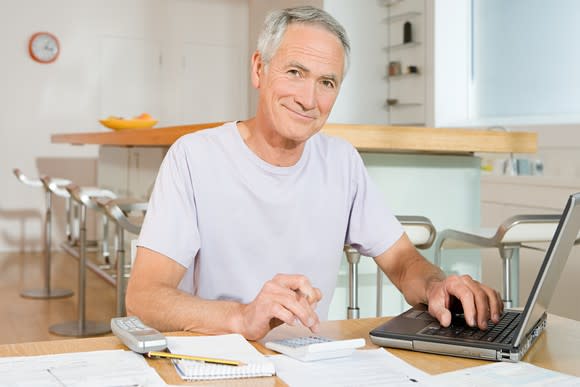 A senior man using his laptop and reviewing his finances.