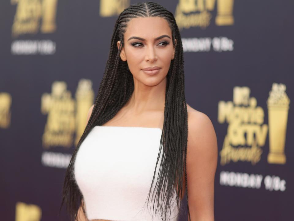 Kim Kardashian wears braids in front of a background that reads MTV Movie and TV Awards