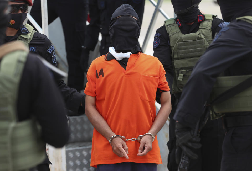 Police officers escort suspected militant Upik Lawanga, center, upon arrival at Soekarno-Hatta International Airport in Tangerang, Indonesia, Wednesday, Dec. 16, 2020. Indonesian authorities on Wednesday transferred suspected militants arrested in recent weeks to the country’s capital. Among them are Aris Sumarsono, known as Zulkarnaen, and Lawanga, the ringleaders of the al-Qaida-linked Jemaah Islamiyah network who have eluded capture for more than a decade. (AP Photo/Achmad Ibrahim)