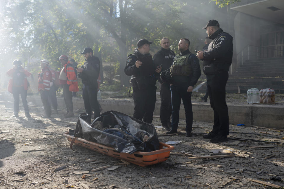 Police officers stand next to the body of a man killed after a drone fired on buildings in Kyiv, Ukraine, Monday, Oct. 17, 2022. Waves of explosive-laden suicide drones struck Ukraine's capital as families were preparing to start their week early Monday, the blasts echoing across Kyiv, setting buildings ablaze and sending people scurrying to shelters. (AP Photo/Roman Hrytsyna)