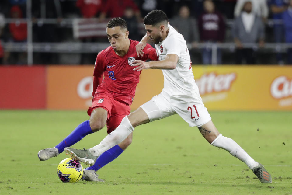 U.S. defender Sergino Dest, left, moves to get position on Canada midfielder Jonathan Osorio (21) during the second half of a CONCACAF Nations League soccer match Friday, Nov. 15, 2019, in Orlando, Fla. (AP Photo/John Raoux)
