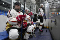 Members of the "1979" hockey club watch the action from the bench during a hockey match at a rink in Beijing, Wednesday, Jan. 12, 2022. Spurred by enthusiasm after China was awarded the 2022 Winter Olympics, the members of a 1970s-era youth hockey team, now around 60 years old, have reunited decades later to once again take to the ice. (AP Photo/Mark Schiefelbein)