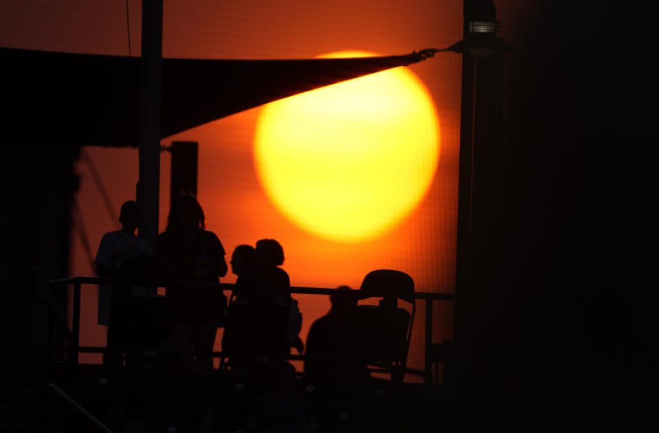 The sun sets as fans wander the main concourse of Coors Field in the fourth inning of a baseball game between the Colorado Rockies and the San Diego Padres on Tuesday, June 15, 2021, in Denver. (AP Photo/David Zalubowski)