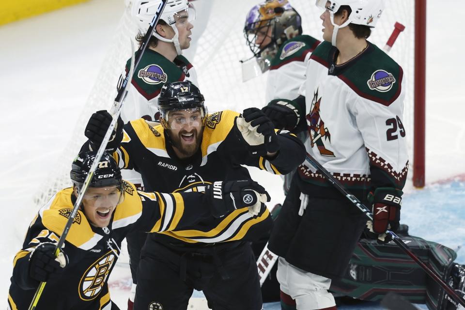 CORRECTS THAT GOAL WAS DISALLOWED - Boston Bruins' Nick Foligno (17) celebrates after an apparent goal against Arizona Coyotes' Karel Vejmelka, second from right, with teammate Hampus Lindholm (27) during the second period of an NHL hockey game Saturday, Oct. 15, 2022, in Boston. The goal was disallowed. (AP Photo/Michael Dwyer)