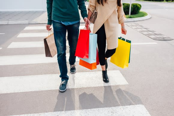 Couple walking down the street with shopping bags.