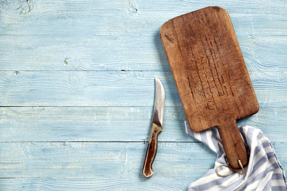 Old chopping board with knife and napkin on wooden table