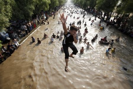 A boy jumps into a water canal to cool himself with others on a hot day in the eastern city of Lahore June 9, 2013. REUTERS/Mohsin Raza