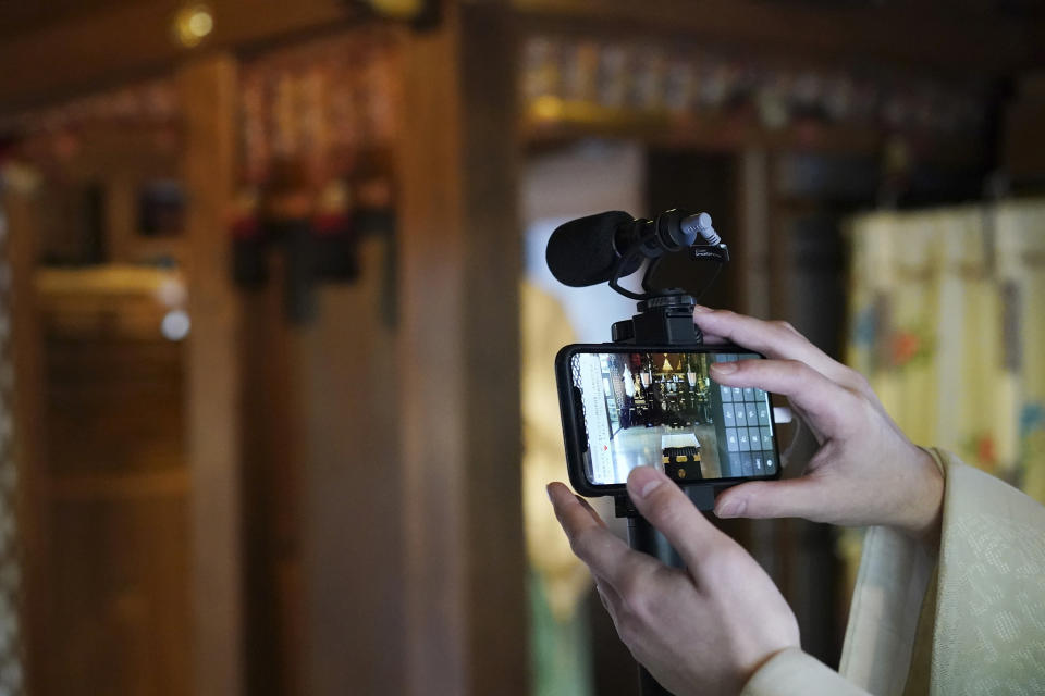 In this May 8, 2020, photo, a priest prepares a livestream prayer during a 10-day trial of "online shrine" visit program at Onoterusaki Shrine in downtown Tokyo, allowing its visitors to join rituals from their homes. The shrine also accepted from worshipers their prayer messages, which were printed on a virtual wooden tablet each and offered to the Shinto gods to keep away evil spirits and the epidemic. (AP Photo/Eugene Hoshiko)