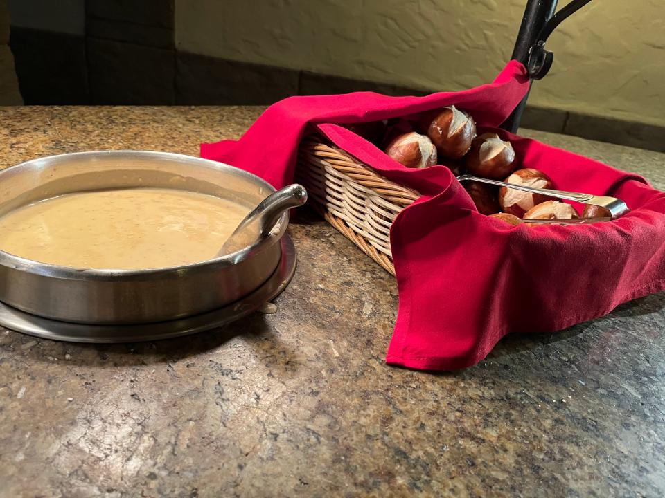 vat of beer cheese soup and basket of pretzel rolls at biergarten restaurant in epcot disney world