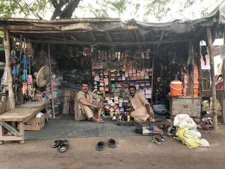 Men sit at a cobbler shop at a market in the town of Rabwah, Pakistan July 9, 2018. Picture taken July 9, 2018. REUTERS/Saad Sayeed