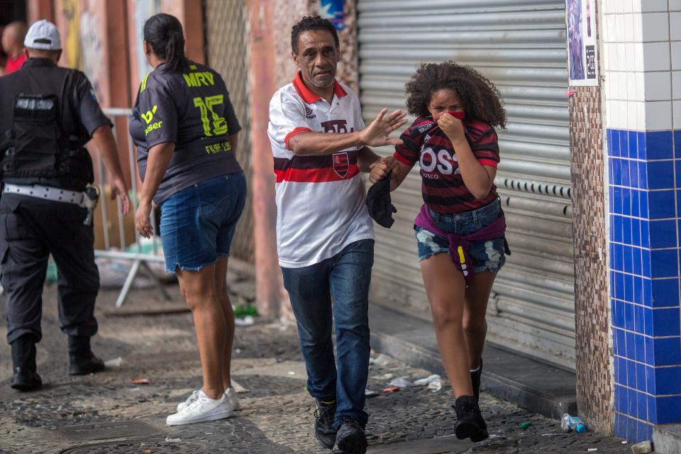 Fans of Flamengo football club taking part in a celebration parade, flee from tear gas shot by riot police after some alleged theft incidents within the crowd, in Rio de Janeiro, Brazil on November 24, 2019. (Photo by Daniel RAMALHO / AFP) (Photo by DANIEL RAMALHO/AFP via Getty Images)