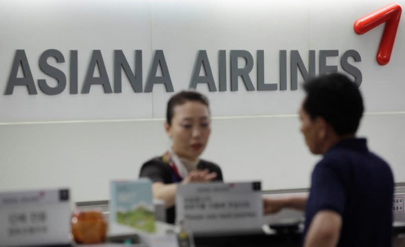FILE PHOTO: A staff of Asiana Airlines speaks to a passenger at Gimpo Airport in Seoul