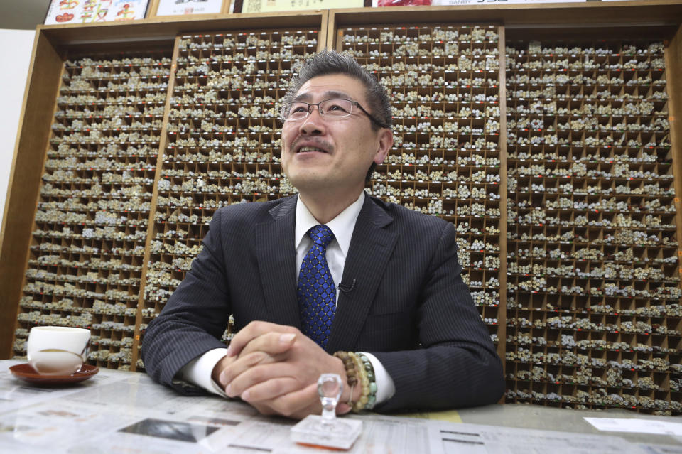 In this April 10, 2019, photo, Shigeo Kojima, managing director Kippodo stamp company, speaks in front of a stack of name stamps during an interview in Tokyo. Japan is getting ready for its biggest celebration in years with the advent of the Reiwa era of soon-to-be emperor Naruhito. Kippodo has been getting 300-500 orders daily for new Reiwa era labeling stamps since the name for the new era was announced on April 1. (AP Photo/Koji Sasahara)