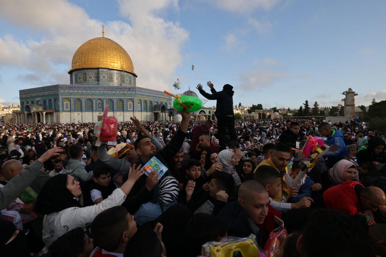 Muslims exchange gifts as they gather on the first day of Eid al-Fitr to celebrate the end of the holy fasting month of Ramadan outside the Dome of the Rock at the Aqsa mosques complex in the Old city of Jerusalem (AFP via Getty Images)