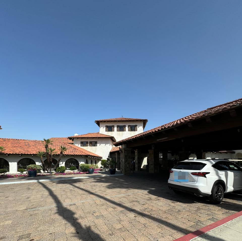 Exterior view of a Spanish-style building possibly serving as a hotel with terracotta roofing and a parked car