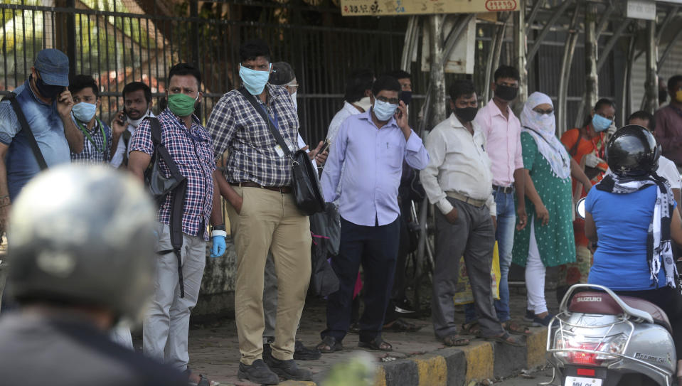 People wait for bus in Mumbai, India, Monday, June 8, 2020. India is reopening its restaurants, shopping malls and religious places in most of its states after a more than 2-month-old lockdown even as the country continues to witness a worrying rise in new coronavirus infections. (AP Photo/Rafiq Maqbool)