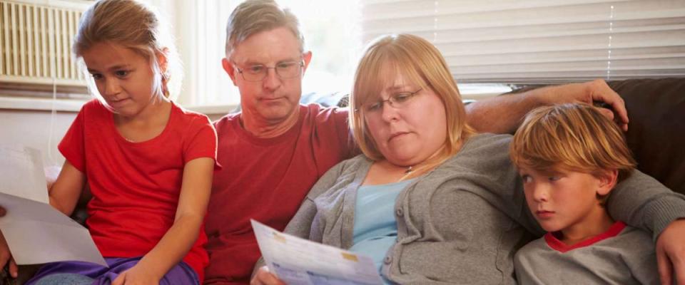 Unhappy Family Sitting On Sofa Looking At Bills