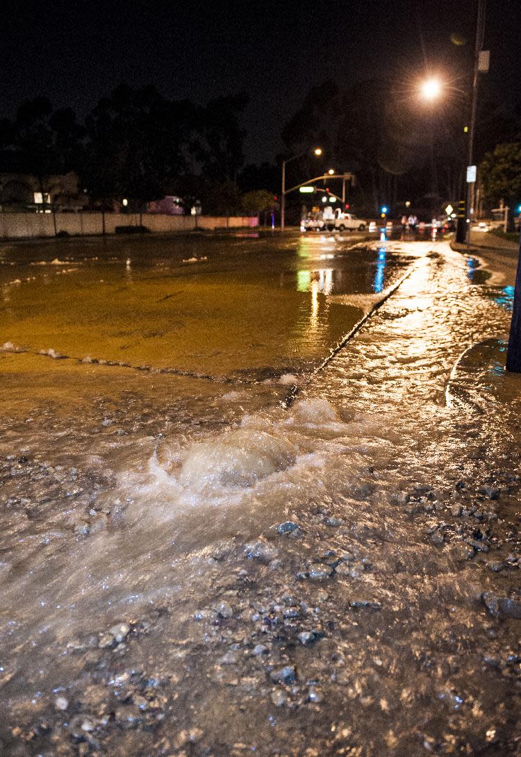 Water bubbles up through the pavement along Gilbert Street just south of Rosecrans in Fullerton Friday night March 28, 2014 following an 5.1 earthquake. Police closed off the street as crews placed cones around the area. (AP Photo/The Orange County Register, Mark Rightmire)