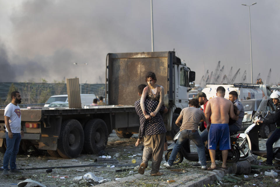 People evacuate wounded after of a massive explosion in Beirut, Lebanon, Tuesday, Aug. 4, 2020. Massive explosions rocked downtown Beirut on Tuesday, flattening much of the port, damaging buildings and blowing out windows and doors as a giant mushroom cloud rose above the capital. Witnesses saw many people injured by flying glass and debris. (AP Photo/Hassan Ammar)