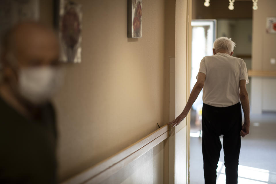 FILE - In this April 16, 2020, file photo, Richard Eberhardt walks along a corridor at a nursing home in Kaysesberg, France. European Union leaders are preparing for a new virtual summit, which will take place Thursday, April 23, 2020, to take stock of the damage the coronavirus has inflicted on the lives and livelihoods of the bloc's citizens and to thrash out a more robust plan to revive their ravaged economies. (AP Photo/Jean-Francois Badias, File)
