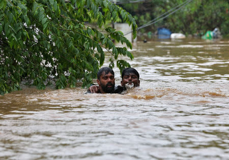 FILE PHOTO: A man rescues a drowning man from a flooded area after the opening of Idamalayr, Cheruthoni and Mullaperiyar dam shutters following heavy rains, on the outskirts of Kochi, August 16, 2018. REUTERS/Sivaram V/File Photo