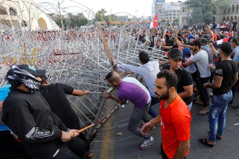 Demonstrators try to remove the fence during a protest over corruption, lack of jobs, and poor services, in Baghdad