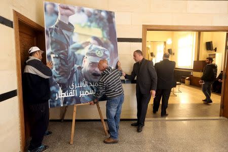 Men place a picture of Lebanese Hezbollah militant leader Samir Qantar, who was killed in an Israeli air strike in Damascus early on Sunday, in Beirut's southern suburbs where his relatives are accepting condolences for his death, December 20, 2015. REUTERS/ Hasan Shaaban