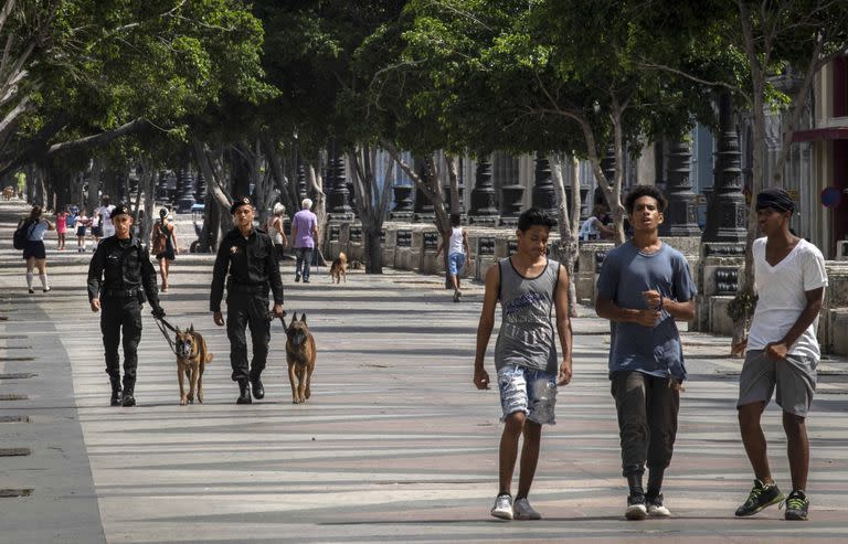 La gente camina en el Paseo del Prado mientras miembros de la policía patrullan en La Habana, Cuba, el lunes 11 de julio de 2022