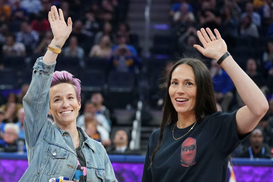 Sue Bird, right, and Megan Rapinoe wave to the crown during a 2019 NBA game between the Golden State Warriors and Phoenix Suns.