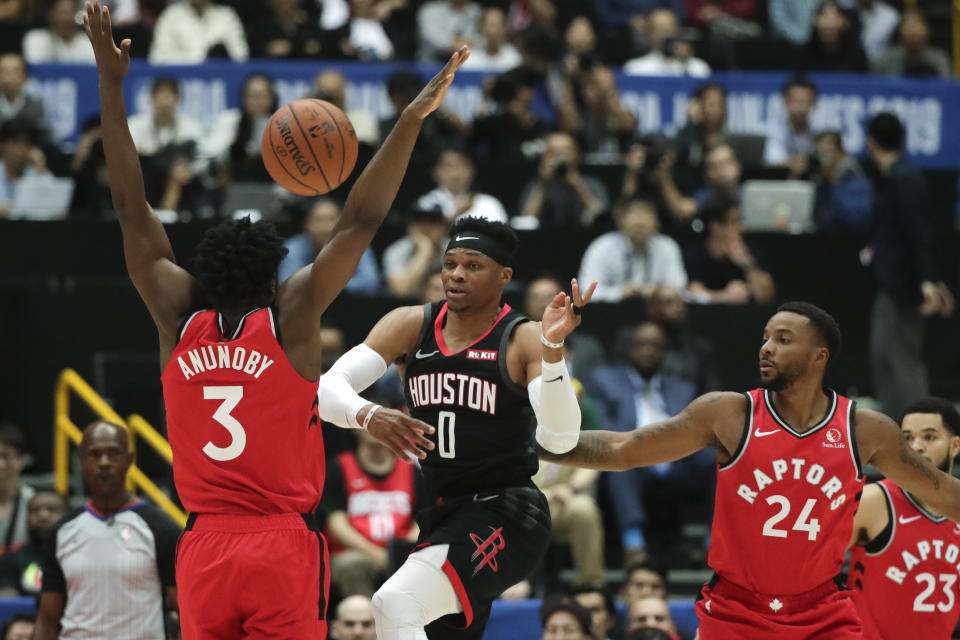 Houston Rockets' Russell Westbrook, center, passes the ball under pressure by Toronto Raptors' OG Anunoby, left, and Norman Powell during the first half of an NBA preseason basketball game Tuesday, Oct. 8, 2019, in Saitama, near Tokyo. (AP Photo/Jae C. Hong)