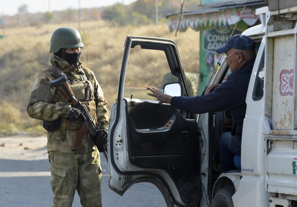 A Kyrgyz army soldier checks a car at a checkpoint in a street in Bishkek, Kyrgyzstan, Monday, Oct. 12, 2020. Kyrgyzstan's president on Monday ordered a new, week-long state of emergency in the country's capital after parliament failed to consider and approve his previous order within the legally required three days. (AP Photo/Vladimir Voronin)