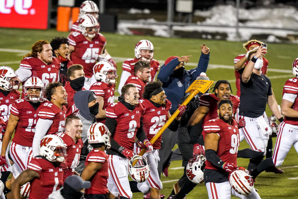 Wisconsin players celebrate with the Paul Bunyan Axe after they defeated Minnesota in overtime of an NCAA college football game Saturday, Dec. 19, 2020, in Madison, Wis. (AP Photo/Andy Manis)