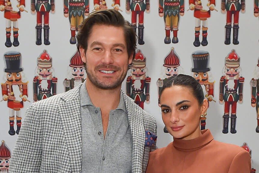 Paige DeSorbo and Craig Conover pose together in front of a nutcracker wallpaper at BravoCon 2023.