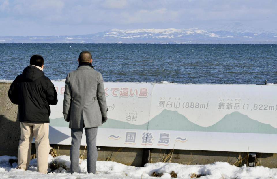 Tourists look at Kunashiri Island, one of four southern Kuril islands, which Japan calls the Northern Territories, from the Notsuke Peninsula in Betsukai in Japan's northernmost major island of Hokkaido Thursday, Dec. 15, 2016. Russian President Vladimir Putin arrived in Japan on Thursday for a two-day summit that marks his first official visit to a G-7 country since Russia's 2014 annexation of Crimea. During two days of talks, Japan's Prime Minister Shinzo Abe hopes to make progress on a long-running territorial dispute over the four islands, while trying to bolster ties with economic projects. Japanese on the board reads: "Kunashiri, the island close but far." (Yoshiaki Sakamoto/Kyodo News via AP)