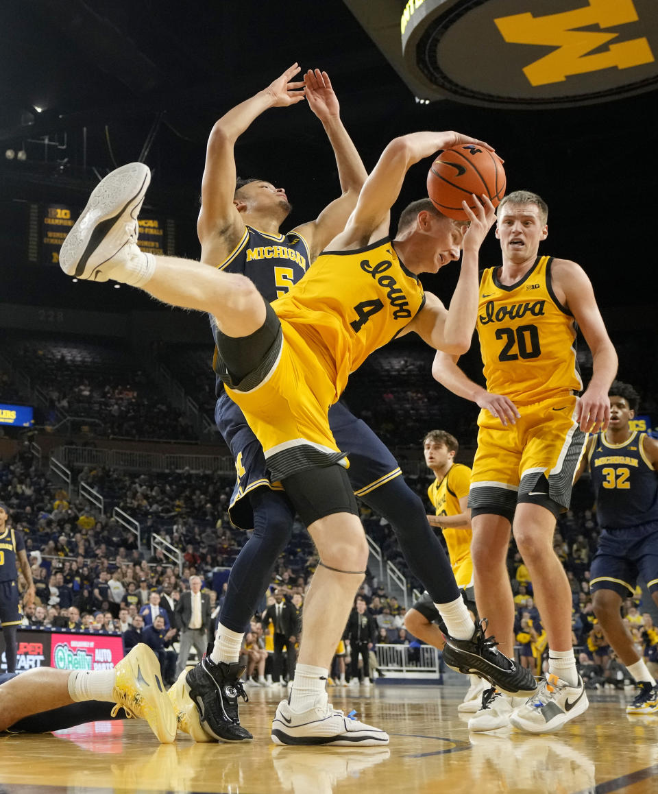 Iowa guard Josh Dix (4) pulls down a rebound next to Michigan forward Terrance Williams II (5) during the second half of an NCAA college basketball game, Saturday, Jan. 27, 2024, in Ann Arbor, Mich. (AP Photo/Carlos Osorio)