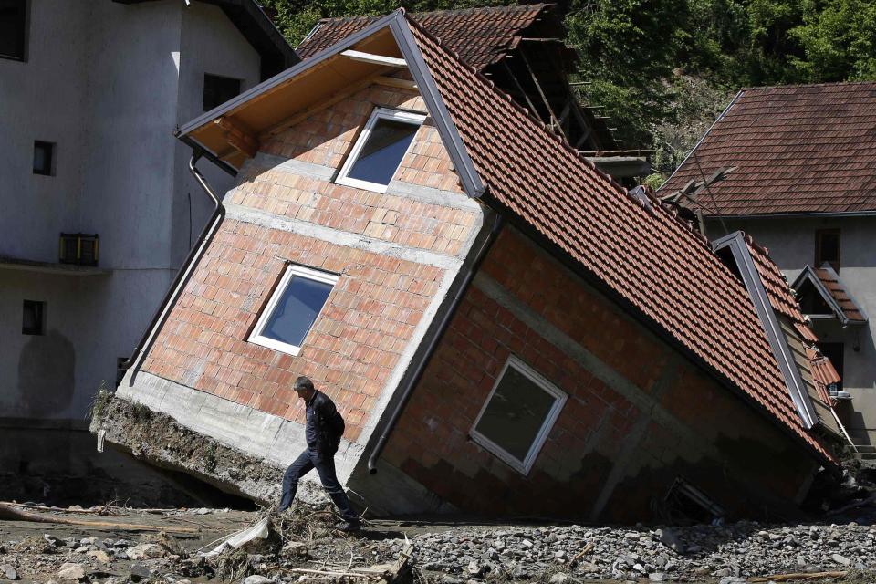 A man walks past a house tilted by floods in the village of Krupanj, west from Belgrade