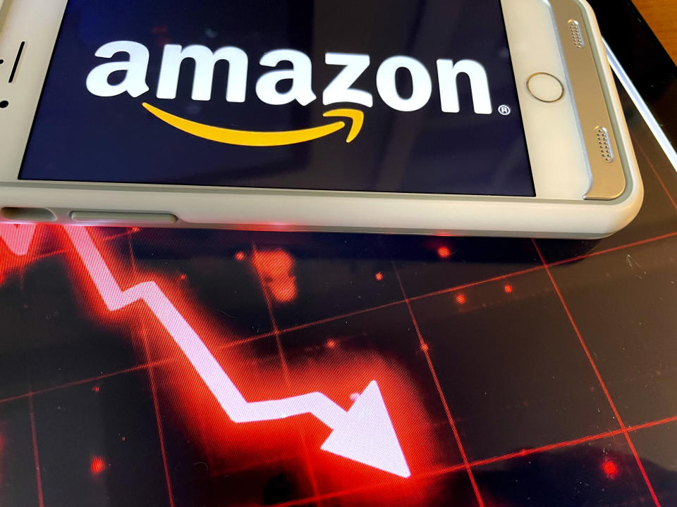 An Amazon logo on a phone and a graph illustration showing a red down arrow.