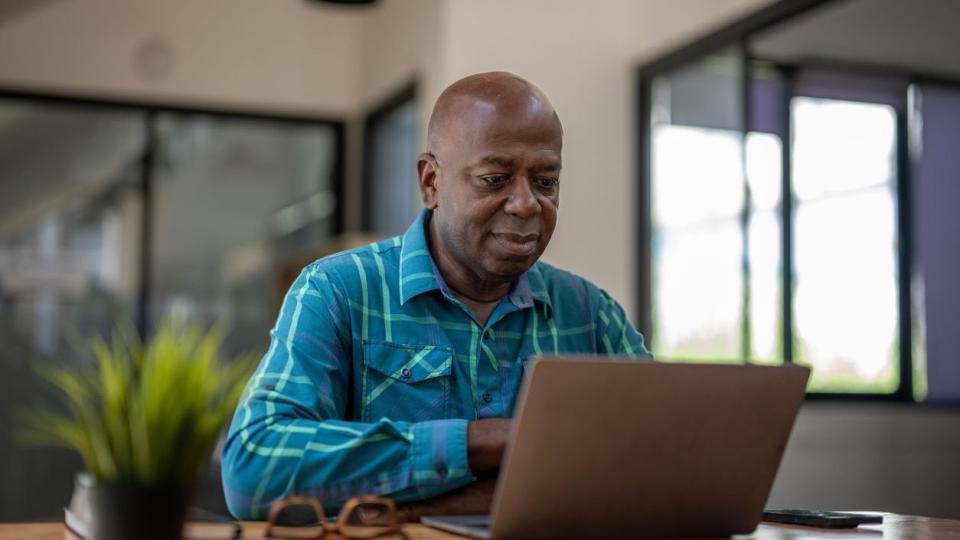 A man looks over his retirement accounts on his laptop. 