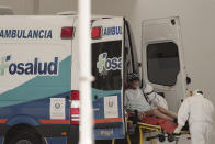 A patient infected with the new coronavirus is transferred from an ambulance onto a stretcher at the National Hospital emergency entrance in San Salvador, El Salvador, Friday, Aug. 7, 2020. For months, the strictest measures confronting the COVID-19 pandemic in Latin America seemed to keep infections in check, in El Salvador, but a gradual reopening combined with a political stalemate has seen infections increase nearly fourfold. (AP Photo/Salvador Melendez)