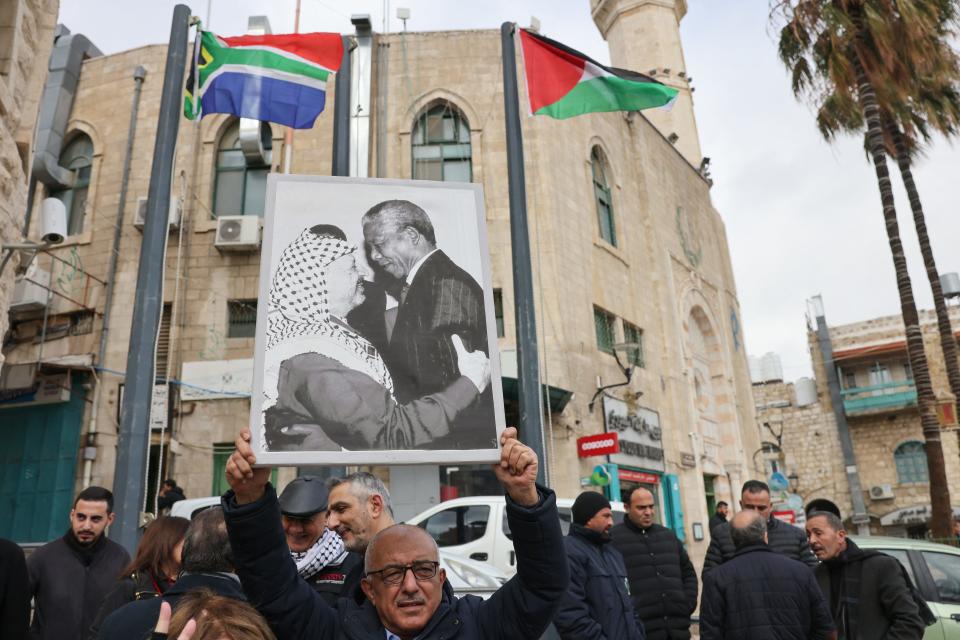 A Palestinian man holds a portrait of late Palestine Liberation Organisation leader Yasser Arafat and South Africa's anti-apartheid icon Nelson Mandela outside a municipality building in Bethlehem in the occupied West Bank, on Jan. 12, 2024.
