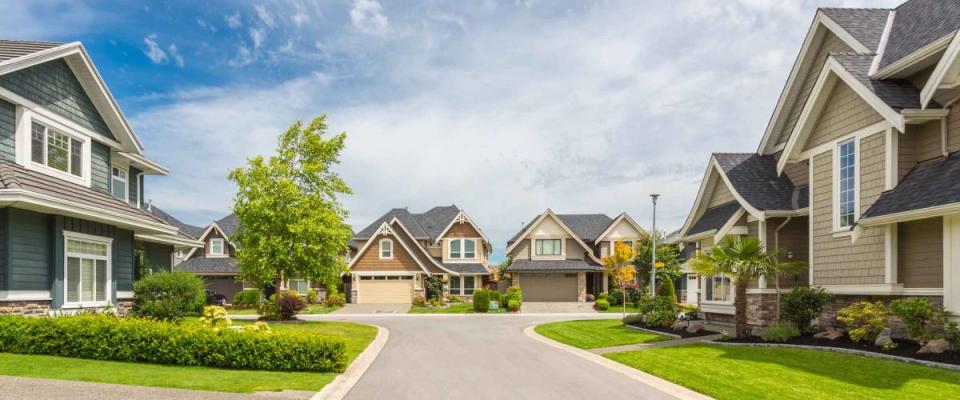 Nicely trimmed and manicured garden in front of a luxury house on a sunny summer day. Street of houses in the suburbs of Canada.